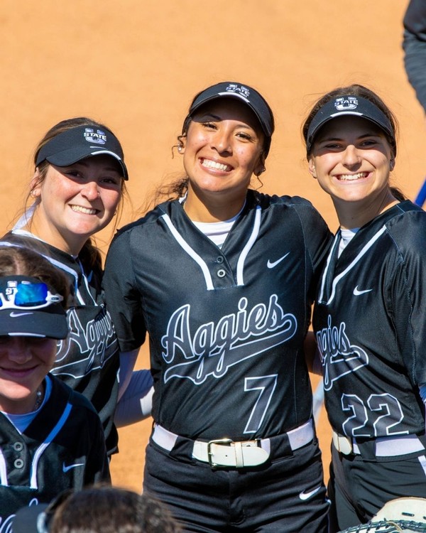 Three USU softball players pose for a photo in the infield